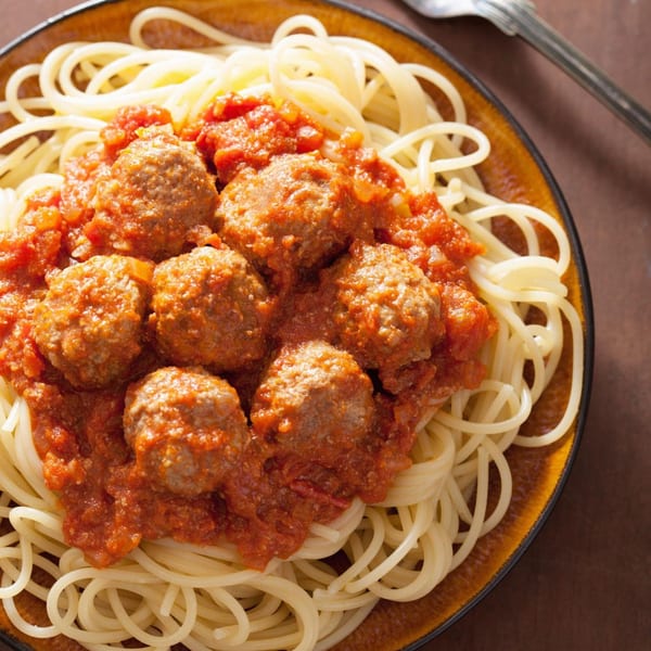 Caruso's spaghetti and meatballs, featuring pasta topped with rich red sauce and savory meatballs.